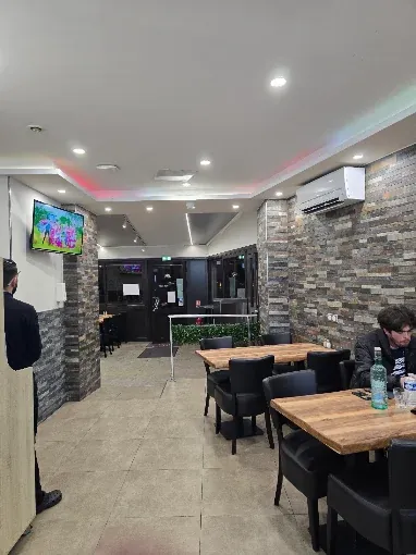 La salle du restaurant : murs en pierre, tables en bois, climatisation