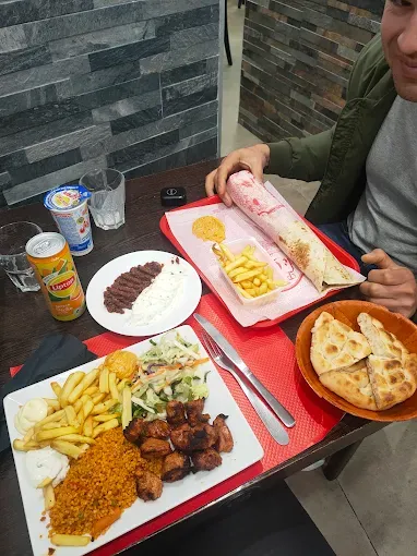 Table garnie : assiette de brochettes, galette, frites et pain